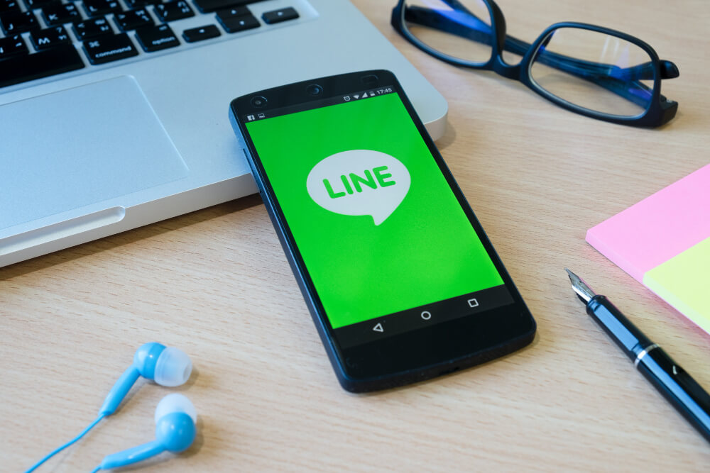 LINEアプリを表示したスマートフォンとパソコンが置かれたデスク。